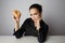 Portrait of a confused beatiful caucasian woman thinking to eat donut or not isolated over white background.