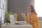 Portrait of confused beautiful stylish dark haired young woman in yellow shirt sitting, looking at laptop screen and shrugging