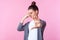 Portrait of confused disgusted teen girl pinching her nose and showing stop sign. isolated on pink background