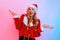 Portrait of confused girl wearing Santa hat showing vague gesture  on background