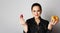 Portrait of a confused smiling caucasian woman choosing between donut and red strawberry isolated over white background