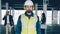Portrait of construction specialist wearing safety uniform standing in empty building with businesspeople in background