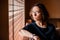 Portrait of a contemplative girl sitting in a chair close to the window