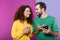 Portrait of content caucasian couple man and woman in colorful clothing smiling and holding cellphones together