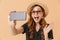 Portrait of content modern woman wearing straw hat and sunglasses laughing and taking selfie photo on smartphone, isolated over b