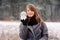 Portrait of a contented young girl holding a magic glass ball on the background of a winter forest.