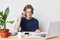 Portrait of convinced self assured male enterpreneur looks seriously through glasses, surrounded with modern laptop, mobile phone