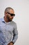 Portrait of a cool Latino man with a beard, sunglasses and a shirt on a white background