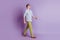 Portrait of cool self-assured guy walk look empty space on purple background