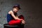 Portrait of cool young hip hop boy in blue hat and red pants sitting on black barrel