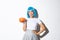 Portrait of coquettish asian girl in halloween costume and blue wig, holding cute pumpkin and winking at camera with