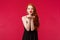 Portrait of coquettish feminine young beautiful redhead woman in black stylish dress, sending air kiss on palms near