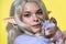 Portrait of cosplay elf young woman holding Sphinx cat in her hands on yellow background