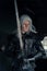 Portrait of cosplayer in image of character Geralt of Rivia from the game or film The Witcher with sword in his arms