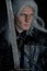 Portrait of cosplayer in image of character Geralt of Rivia from the game or film The Witcher with sword in his arms