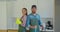 Portrait of a couple as a professional cleaners in uniform standing together with cleaning tools indoors.