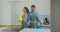 Portrait of a couple as a professional cleaners in uniform standing together with cleaning tools indoors.