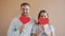 Portrait of couple girl and guy covering faces with heart shape valentine cards