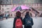 Portrait of couple with pink umbrella on cobbles place in the city