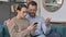 Portrait of Couple Reacting to Loss on Smartphone, Sitting on Sofa