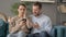 Portrait of Couple Reacting to Loss on Smartphone, Sitting on Sofa