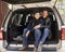 Portrait of couple sitting in open back of car before hiking