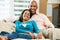 Portrait Of Couple Sitting On Sofa Together