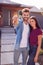 Portrait Of Couple Standing Outdoors In Front Of House With For Sale Sign In Garden Holding Keys