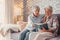 Portrait of couple of two cute grandparents reading a book together sitting on the sofa. Grandmother and grandfather relaxing