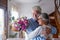 Portrait of couple of two happy and in love seniors or mature and old people holding flowers at home looking outside. Pensioners