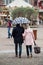 Portrait of couple with umbrella walking on cobbles place in the city