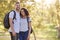 Portrait Of Couple Wearing Backpacks Hiking In Park Together