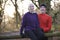 Portrait Of Couple On Winter Run Through Woodland Sitting On Fen