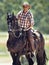 Portrait, cowboy and man riding horse with saddle on field in countryside for equestrian or training. Nature, summer and