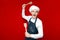 Portrait of a crazy chef on a red isolated background, kitchen worker in uniform with kitchen utensils