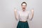 Portrait of crazy funny beautiful young woman in striped shirt and green skirt and collected ban hairstyle, standing with rock