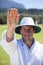 Portrait of cricket umpire signaling bye sign during match