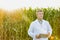 Portrait of crop scientist standing while holding digital tablet against corn plants growing in field with yellow lens flare in ba