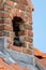 A portrait of a crow sitting in its nest which it made inside of a chimney. The bird is looking around like it is keeping watch