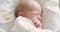 Portrait of crying hungry newborn baby taking hands in mouth, face closeup.