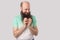 Portrait of cunful funny middle aged bald man with long beard in light green t-shirt standing, looking at camera with new cunning