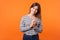 Portrait of cunning smart cute woman with brown hair in long sleeve striped shirt. indoor studio shot isolated on orange