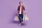 Portrait of curious stylish guy walk step carry shop bargains look up empty space on purple background