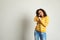 Portrait of curly African-American woman singing in microphone near brick wall.