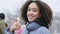 Portrait of curly beautiful positive african american teen girl standing outdoors in city wears warm outerwear shows