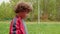 Portrait curly boy walking in green park. Dolly shot teenager boy walking in park on trees landscape. Cute boy looking