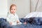 Portrait of cute 8 month old baby girl sitting on the bed on oversize knitted blanket