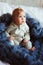 Portrait of cute 8 month old baby girl sitting on the bed on oversize knitted blanket