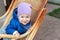 Portrait of cute adorable caucasian baby boy having fun sitting in  wooden rattan rocking chair on house terrace backyard outdoors