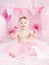 Portrait of cute adorable Caucasian baby girl with blue eyes in pink tutu skirt celebrating her first birthday with gourmet cake